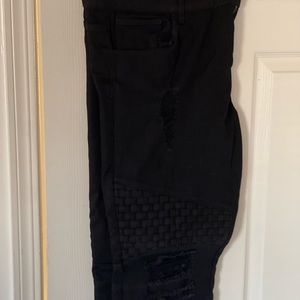 Black jeans with a few rips and weaved pattern above the thigh